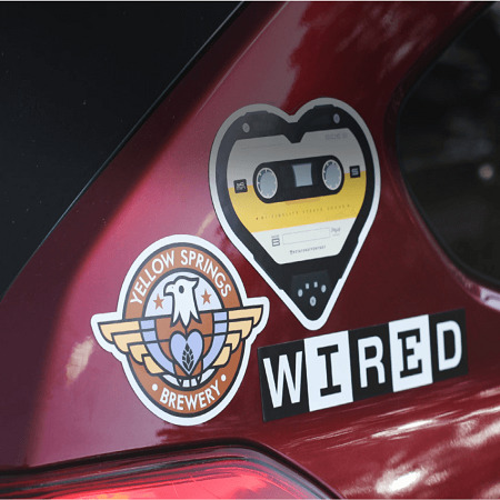 Czerwony samochód z naklejkami: logo browaru Yellow Springs, kaseta w kształcie serca i napis WIRED.