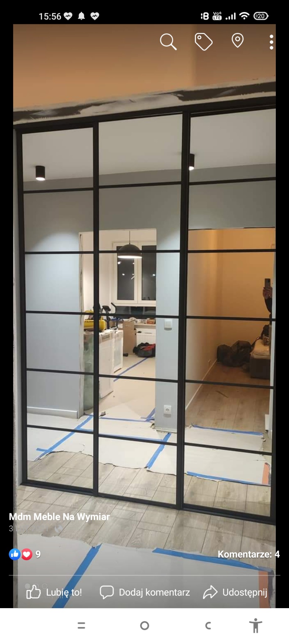 Montaż szklanej ścianki działowej z czarnymi profilami w mieszkaniu, zabezpieczona podłoga folią i taśmą malarską, widok na kuchnię w tle.