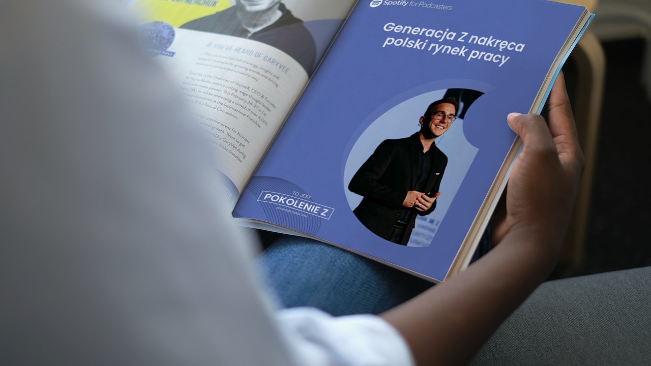 Otwarta gazeta z artykułem o Generacji Z na rynku pracy, stworzonym dla podcastu Spotify, trzymana w dłoni.