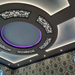 SAMBUD Oleksandr Subbotenko - Dekoracyjny sufit podwieszany z oświetleniem LED i wzorzystą tapetą w tle. Okrągły element z fioletową obwódką i ażurowe panele dodają elegancji wnętrzu.