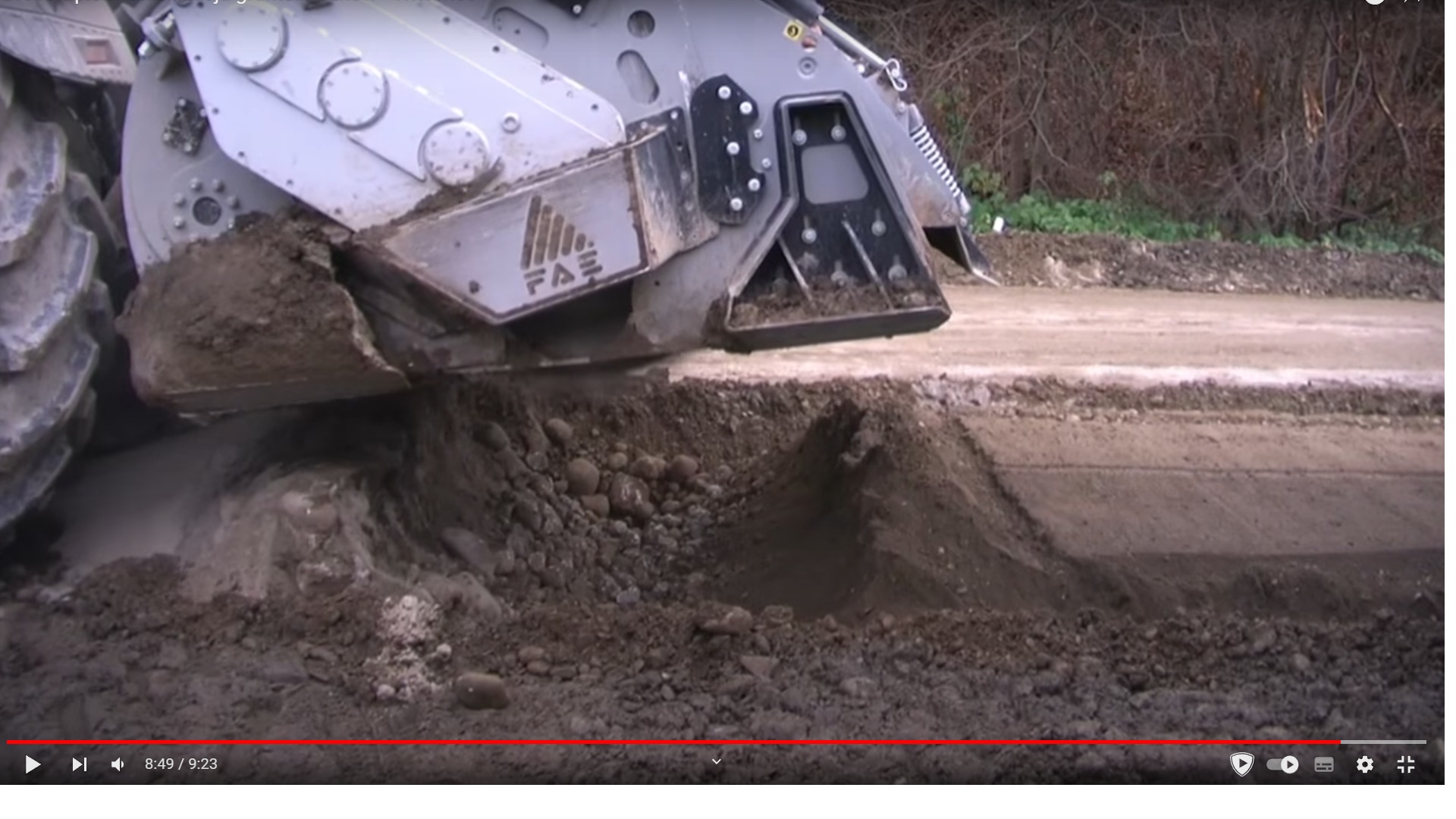 Specjalistyczna maszyna frezuje ziemię, przygotowując teren pod trawnik z rolki, widoczne świeżo obrobione podłoże i duże koło maszyny.