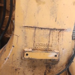 S Technik Sergiy Naumov - Fragment pomalowanej na żółto konstrukcji metalowej z widocznymi śladami rdzy i numerem seryjnym, obok widoczny fragment buta roboczego.