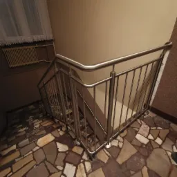 Wewnętrzna klatka schodowa z balustradą ze stali nierdzewnej, widok z góry na mozaikową podłogę, z oknem z firanką w tle.