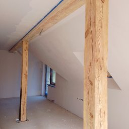 Jacek M - Poddasze w trakcie remontu: drewniane belki konstrukcyjne z widocznym uszczelnieniem taśmą malarską, ściany po szpachlowaniu, przygotowane do malowania.