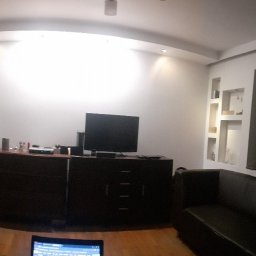 Jacek M - Pokój w trakcie remontu, z widoczną ścianą po wstępnym przygotowaniu pod malowanie lub wykończenie, meblami i sprzętem RTV w tle.