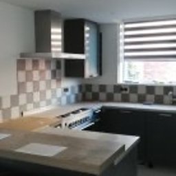 PHU POOLKRING Agnieszka Zenker - Nowoczesna kuchnia z szarymi szafkami i płytkami w szachownicę. Widoczny okap i wyspa kuchenna. Minimalistyczny design z roletami w oknie.