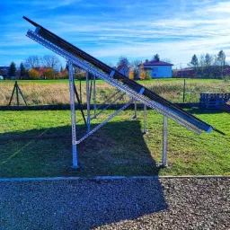 Montaż stelaża pod panele fotowoltaiczne na trawniku w Rzeszowie, widoczne elementy konstrukcyjne i przygotowane podłoże z kamienia.