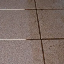 Porównanie czystości brązowych płytek podłogowych z jasną fugą, widoczna różnica między wyczyszczoną i zabrudzoną powierzchnią.