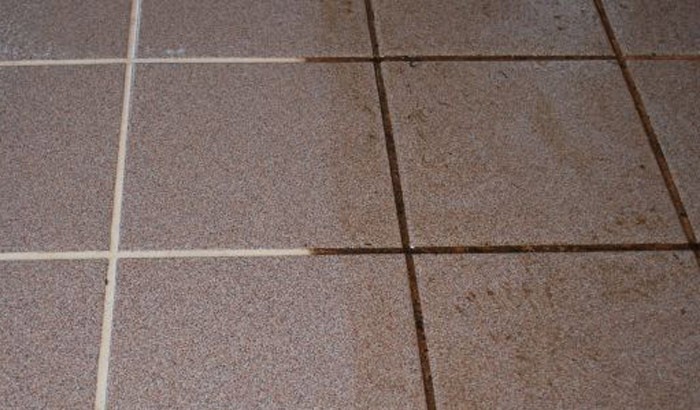 Porównanie czystości brązowych płytek podłogowych z jasną fugą, widoczna różnica między wyczyszczoną i zabrudzoną powierzchnią.