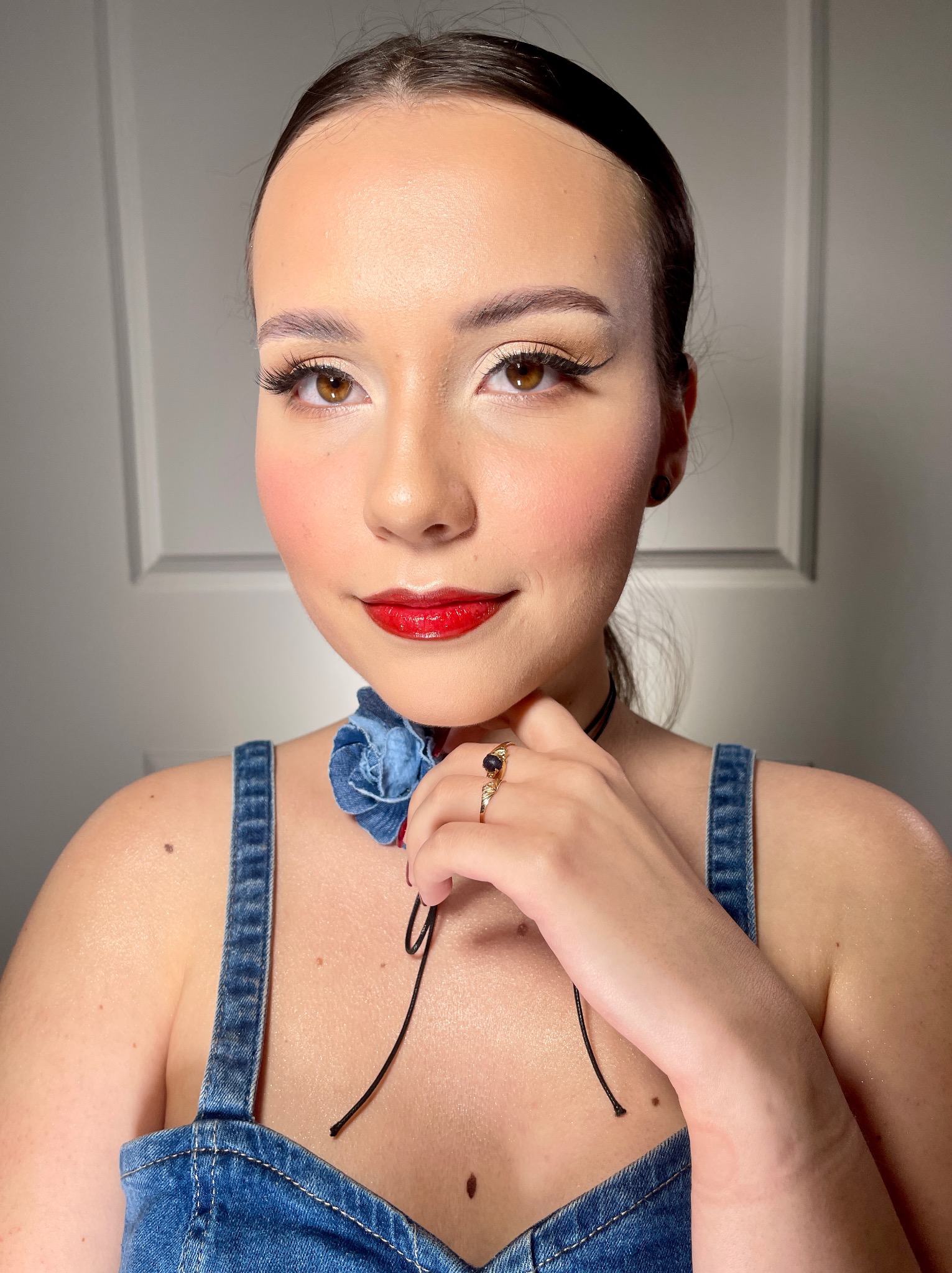 Portret kobiety ze starannym makijażem i chokerem w Szczecinie. Widoczne precyzyjne kreski, czerwone usta i delikatny róż na policzkach.