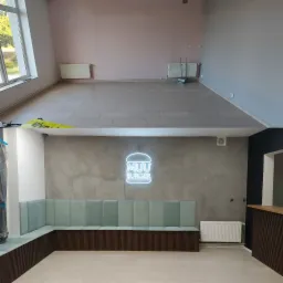 Zdjęcie przedstawia metamorfozę wnętrza lokalu gastronomicznego: górna część ukazuje stan surowy z grzejnikami i surowymi ścianami, dolna część prezentuje efekt po remoncie z tapicerowaną ławą...