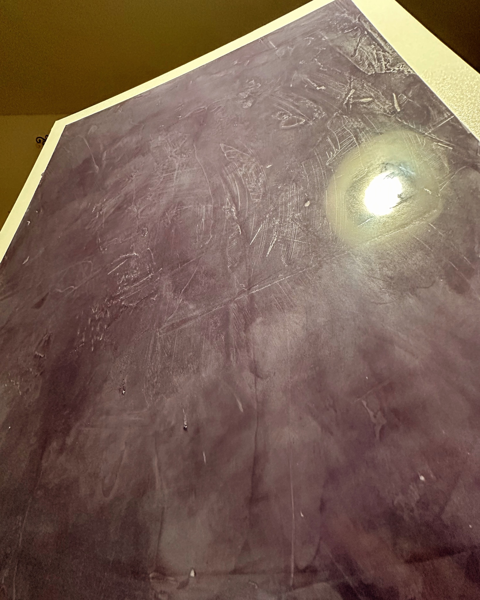 Fioletowa ściana z efektem dekoracyjnym, widoczne ślady po szpachelce i refleks światła.
