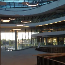 Wnętrze budynku w stanie surowym w Gorzowie Wielkopolskim z widoczną szklaną konstrukcją dachu i oświetleniem oraz elementami szalunków na podłodze.