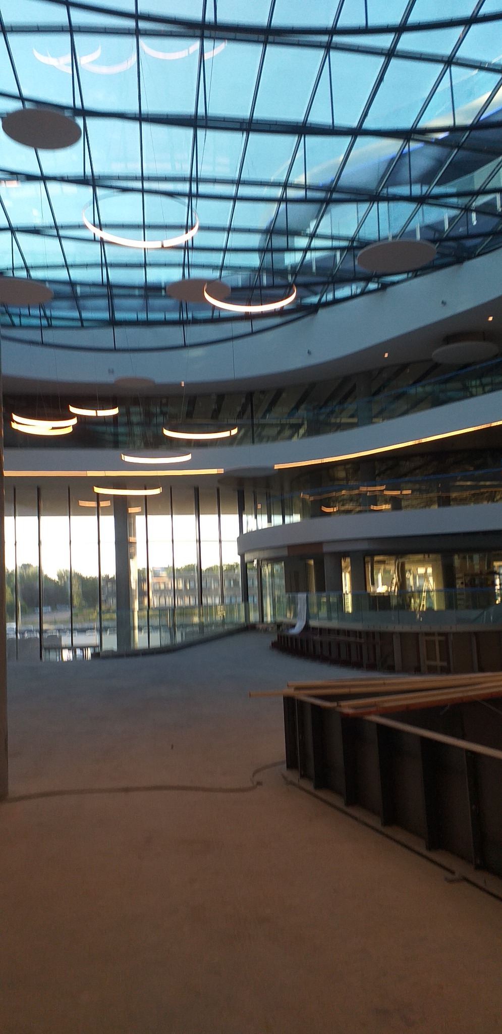 Wnętrze budynku w stanie surowym w Gorzowie Wielkopolskim z widoczną szklaną konstrukcją dachu i oświetleniem oraz elementami szalunków na podłodze.