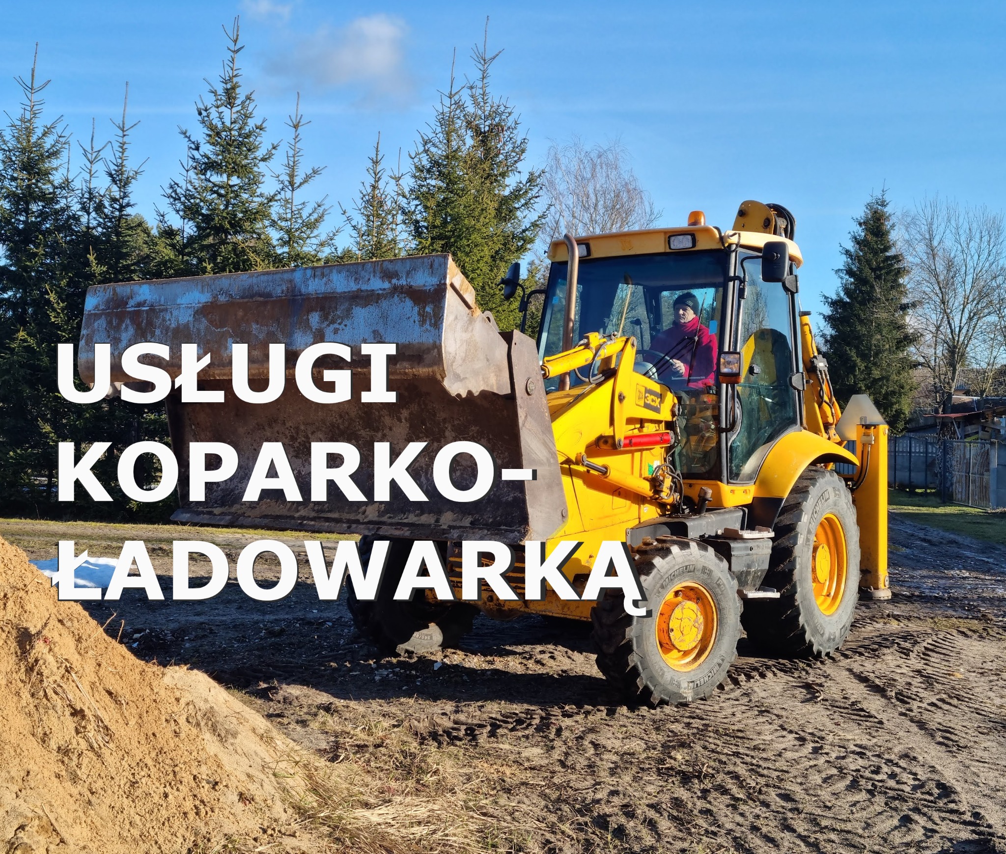 Żółta koparko-ładowarka JCB 3CX z operatorem w kabinie, na nierównym terenie obok sterty piasku, w tle iglaste drzewa i błękitne niebo.