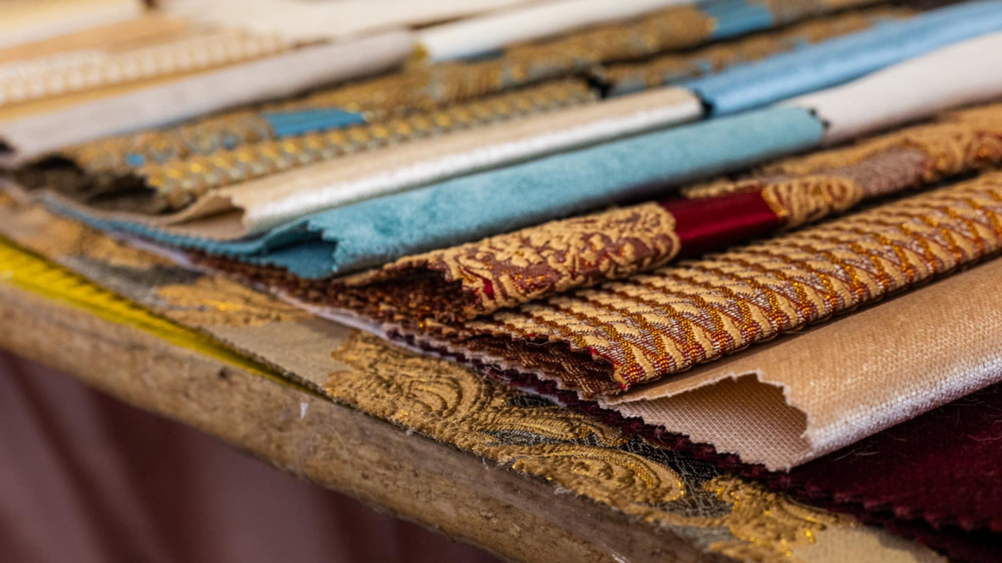 Bogaty wybór tkanin dekoracyjnych: aksamit, żakard, brokat. Paleta barw i faktur, idealna do aranżacji okien. Materiały ułożone warstwami, prezentacja próbek.