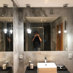 dts dariusz stańczak - Nowoczesna łazienka z marmurowymi płytkami, wiszącą umywalką i lustrem, w którym odbija się osoba robiąca zdjęcie.