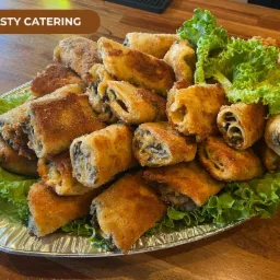 Smażone krokiety z farszem grzybowym ułożone na srebrnej tacy z dekoracją z sałaty, przygotowane przez firmę z Bolesławca.