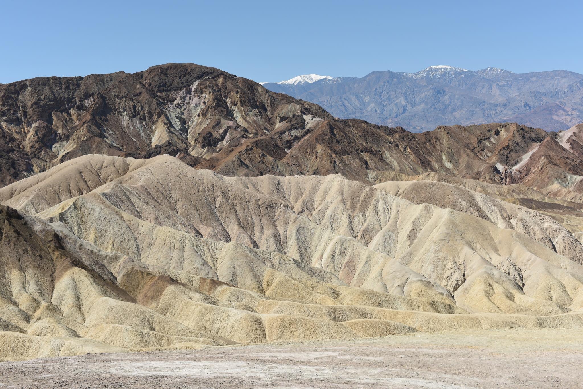 Panoramiczny widok na górzysty krajobraz w okolicach Brzegu, z charakterystycznymi warstwowymi formacjami skalnymi i ośnieżonymi szczytami w oddali pod błękitnym niebem.