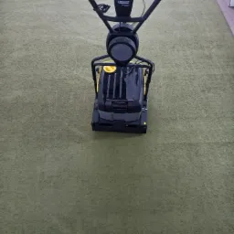 Profesjonalna maszyna Karcher do czyszczenia dywanów na zielonym dywanie w pomieszczeniu.