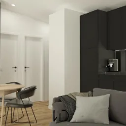 Wizualizacja wnętrza mieszkania: salon z aneksem kuchennym w ciemnej kolorystyce, okrągły stół z krzesłami i szara sofa z poduszkami.