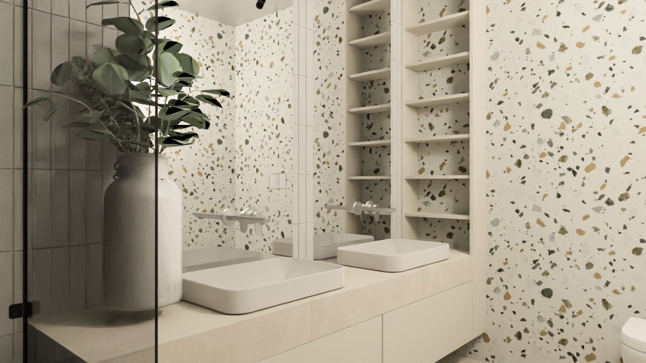 Nowoczesna łazienka z umywalką nablatową, szafką w kolorze kremowym, ścianami wykończonymi płytkami lastryko oraz rośliną w wazonie, widok przez szklaną kabinę prysznicową.