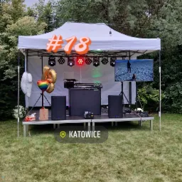 Scena plenerowa pod białym namiotem, przygotowana do imprezy osiemnastkowej, z nagłośnieniem, oświetleniem, ekranem wyświetlającym plażę i balonami w kształcie cyfr.