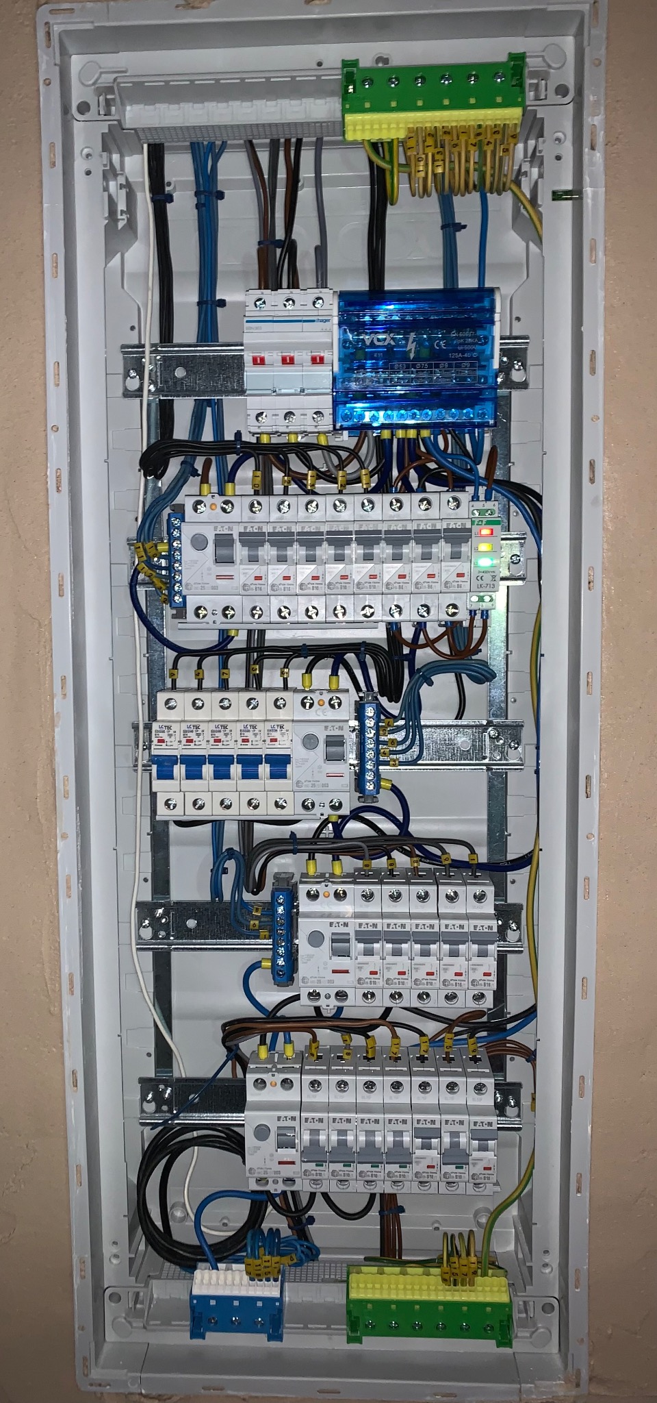 Rozdzielnica elektryczna z zainstalowanymi bezpiecznikami, modułem VOX i listwami zaciskowymi, widoczne okablowanie i elementy montażowe wewnątrz obudowy.