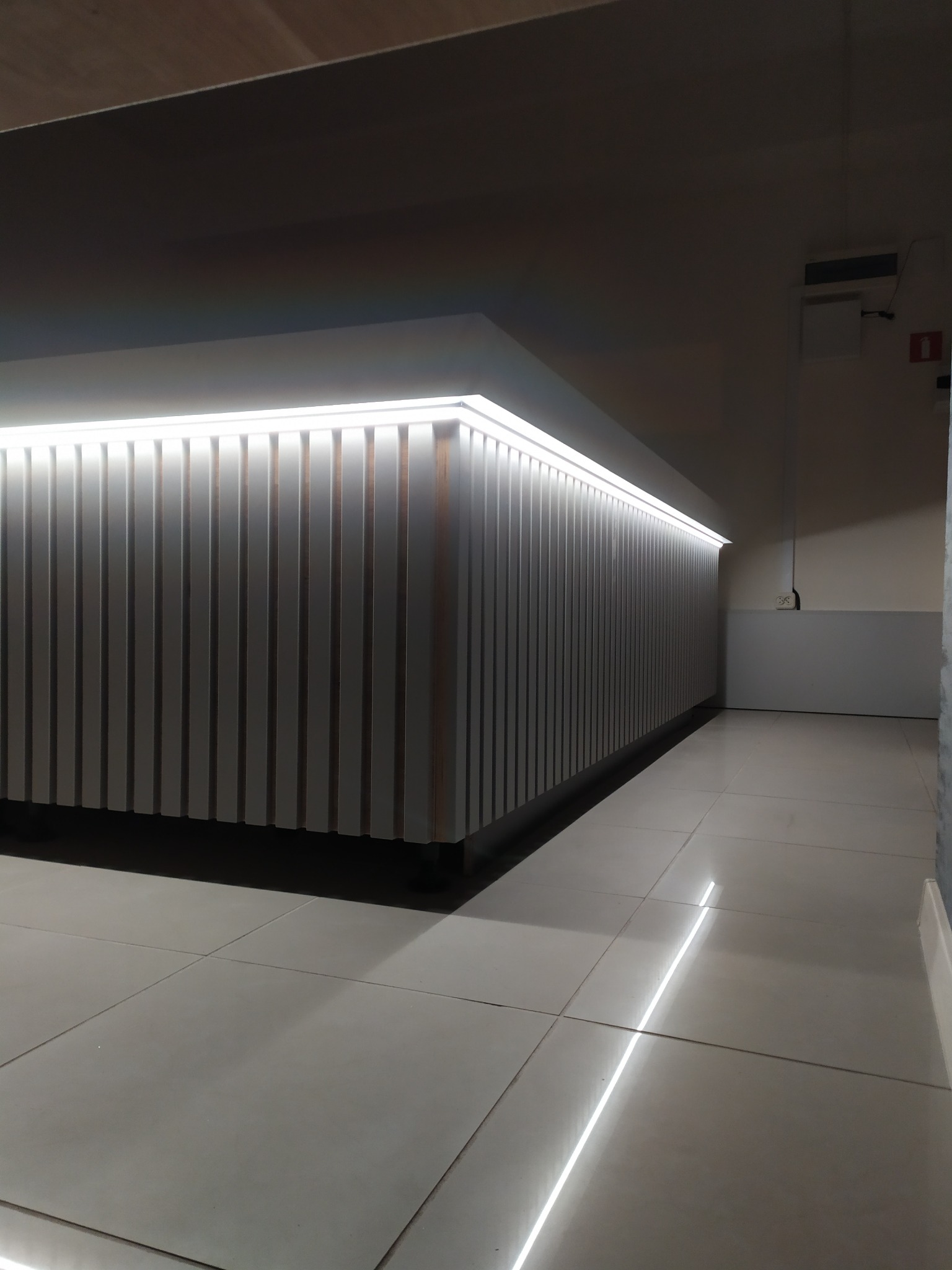 Nowoczesna zabudowa z pionowych paneli z podświetleniem LED, widok z perspektywy podłogi, szara podłoga z płytkami.