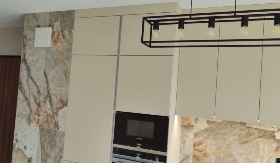 Jasna zabudowa kuchenna z piekarnikiem Siemens, marmurowym panelem i geometryczną lampą wiszącą, widok z dołu.