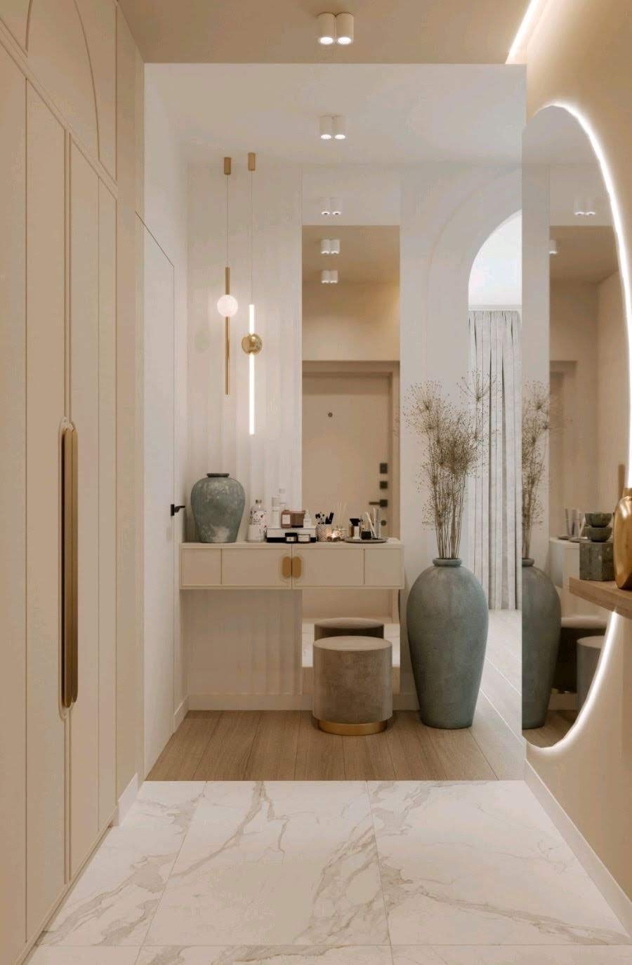 Jasne wnętrze przedpokoju z toaletką, lustrem z podświetleniem LED, dekoracyjnymi lampami wiszącymi i marmurową podłogą.