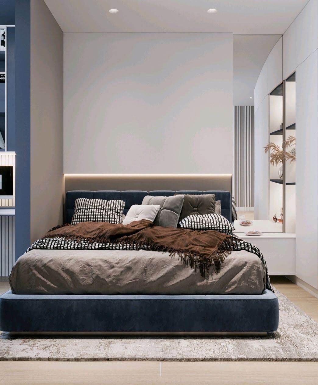 Nowoczesna sypialnia z łóżkiem w kolorze granatowym, ozdobiona brązowym pledem i wzorzystymi poduszkami, z subtelnym oświetleniem LED za wezgłowiem i minimalistycznymi szafkami nocnymi.