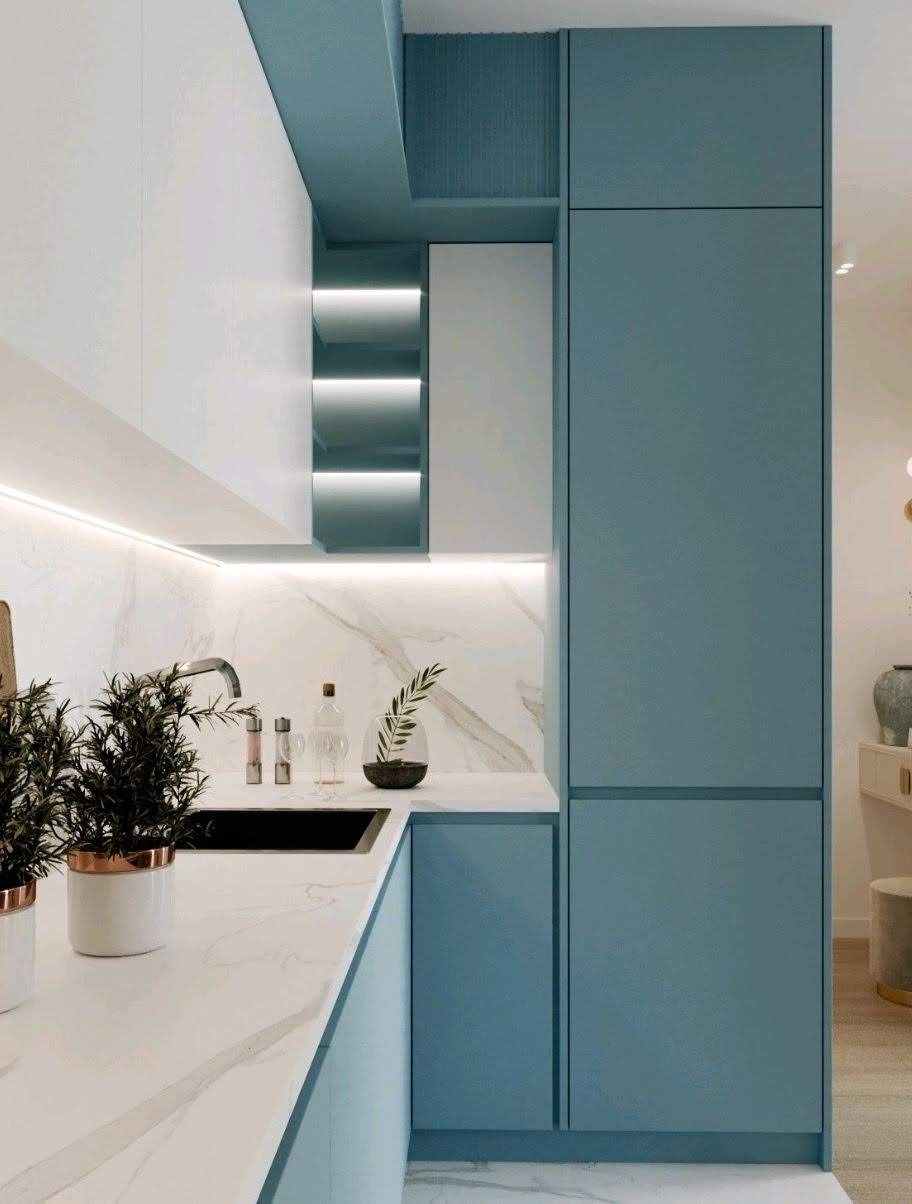 Nowoczesna kuchnia z białymi i błękitnymi szafkami, marmurowym blatem, podświetlanymi półkami i ziołami w doniczkach z miedzianymi akcentami.