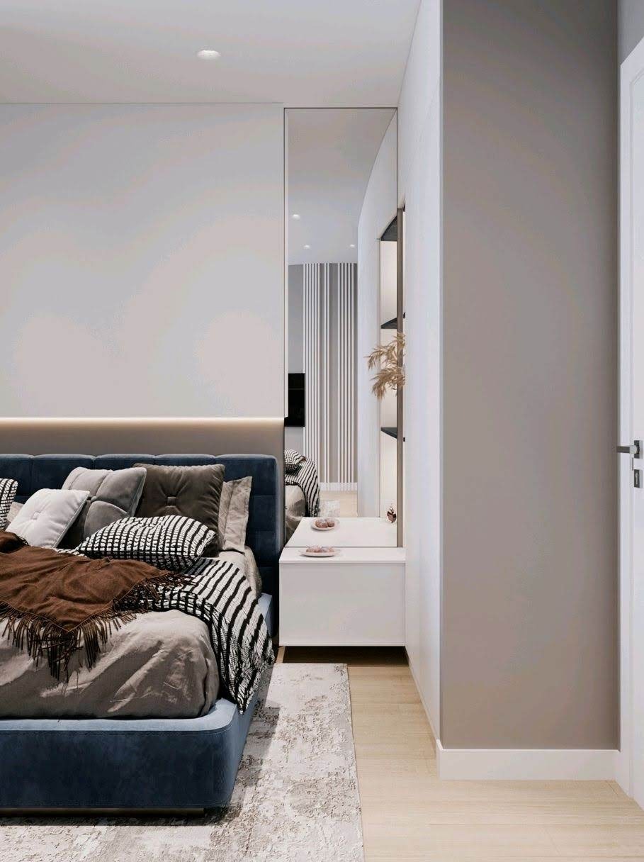 Nowoczesna sypialnia z niebieskim łóżkiem, wzorzystą pościelą, brązowym pledem i białą szafką nocną z lustrem, minimalistyczne wnętrze z drewnianą podłogą i szarymi ścianami.