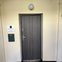 Wejście do kancelarii radcy prawnego Igora Acury Mowicza, z szarą skrzynką na listy numer 25 i tabliczką informacyjną na beżowej ścianie.