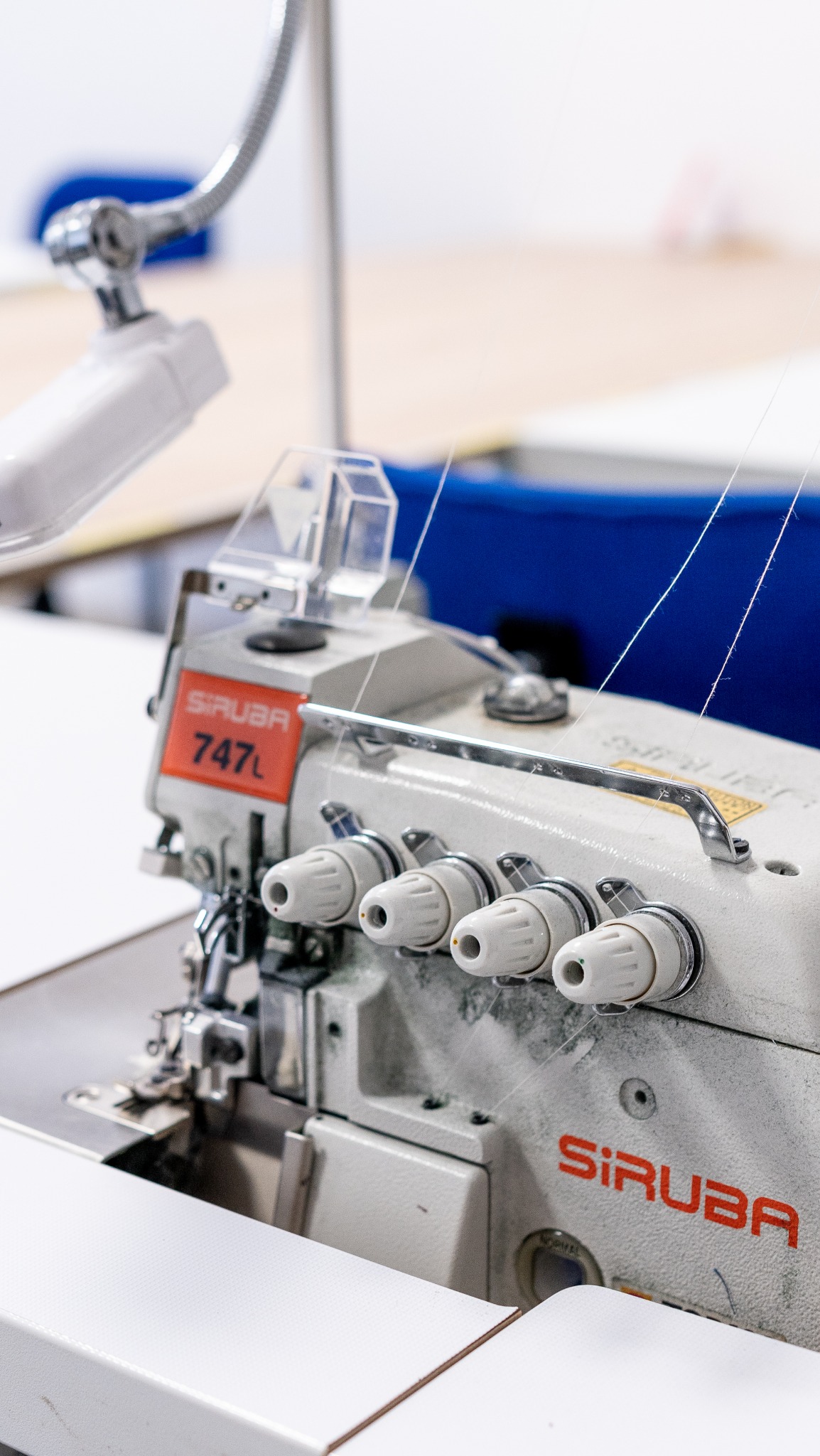 Profesjonalna maszyna szwalnicza Siruba 747L z czterema nićmi, gotowa do szycia. Widoczne detale mechanizmu i naprężaczy nici.
