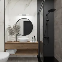 Nowoczesna łazienka z drewnianą szafką pod umywalką, okrągłym lustrem, białą umywalką nablatową, marmurowymi płytkami na ścianie i kabiną prysznicową z czarną armaturą.