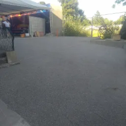 Nowa nawierzchnia z drobnego kruszywa na posesji w Gozdnie, widoczna scena z zadaszeniem w tle i barierka schodów po lewej.