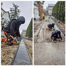 Zloty Ogród - Dwóch pracowników w trakcie montażu obrzeży chodnika na posesji. Jeden ubija gumowym młotkiem, drugi mierzy poziom. W tle domy i tuje.