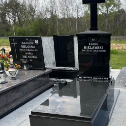 Granis Kamieniarstwo - Czarny, podwójny pomnik z krzyżem na cmentarzu, z inskrypcjami i zdjęciami zmarłych, otoczony drzewami i zielenią.