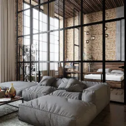 Loftowe wnętrze z szarą sofą modułową, szklaną ścianą działową z czarnymi szprosami, ceglaną ścianą i drewnianym sufitem kasetonowym.