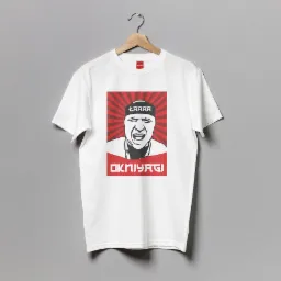 Biała koszulka z nadrukiem w stylu plakatu propagandowego, przedstawiająca krzykliwą postać z napisem 'ŁAAAA' na opasce i 'OKNIYAGI' poniżej, zawieszona na drewnianym wieszaku na szarym tle.