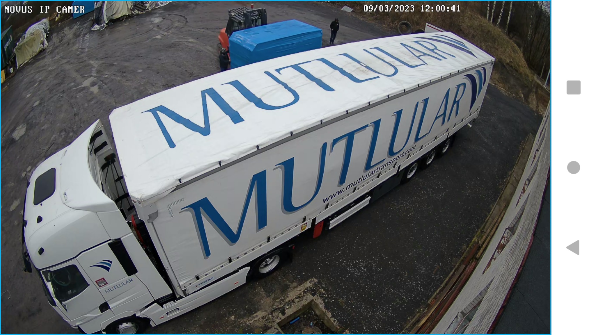 Ciężarówka firmy transportowej Mutlular na placu, widoczny wózek widłowy i pracownicy, ujęcie z kamery przemysłowej.