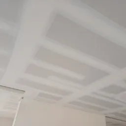 Sufit z płyt kartonowo-gipsowych ze szpachlowanymi łączeniami, widoczne profile i płyty w trakcie prac wykończeniowych.