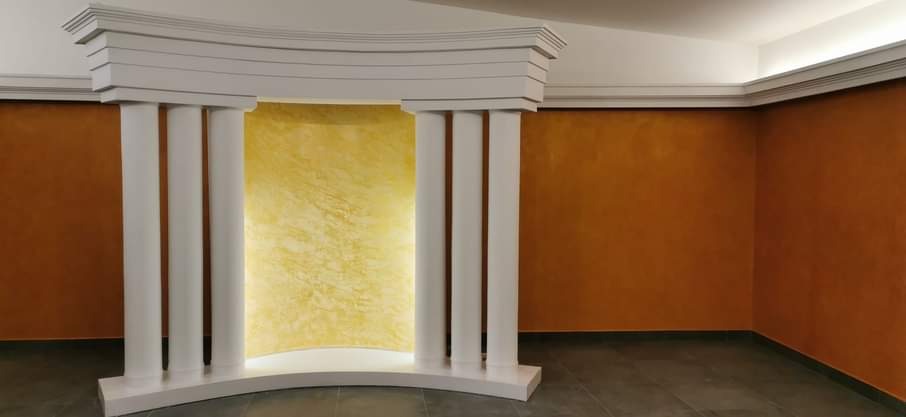 Dekoracyjna wnęka z kolumnami i tłem w odcieniach złota, ściany w kolorze terakoty, wykończenie wnętrza.