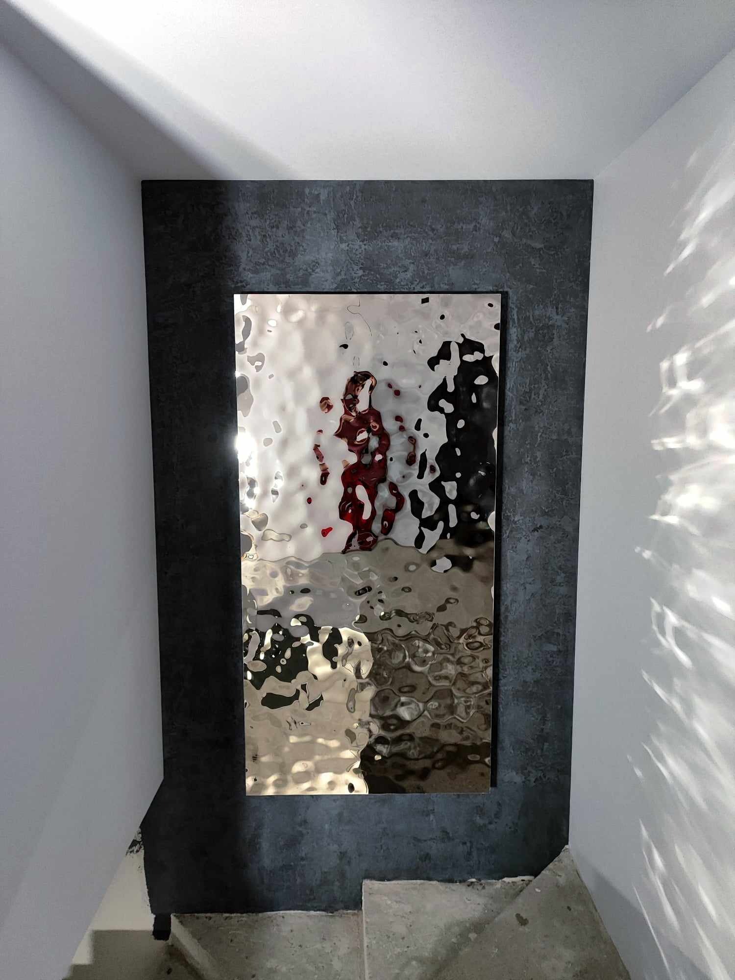 Zabudowa z panelem dekoracyjnym, wkoło wykończona tynkiem dekoracyjnym typu imitacja betonu