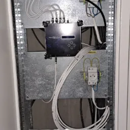 Rozdzielnica elektryczna z zamontowanym wzmacniaczem sygnału ALPHA+ i gniazdem 230V, instalacja wykonana we Wrocławiu, widoczne przewody i złącza.