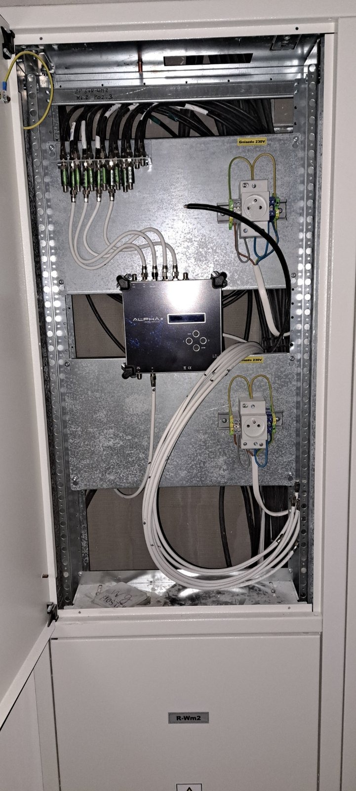 Rozdzielnica elektryczna z zamontowanym wzmacniaczem sygnału ALPHA+ i gniazdem 230V, instalacja wykonana we Wrocławiu, widoczne przewody i złącza.