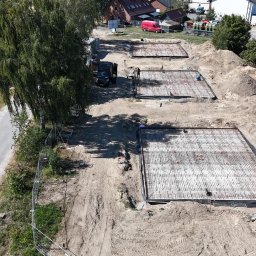 BOEK usługi budowlane Eduard Krynitski - Zbrojenie fundamentów pod budowę w Szczecinie, widok z góry. Trzy kwadratowe obszary z siatką zbrojeniową, przygotowane do zalania betonem. Prace budowlane w toku.