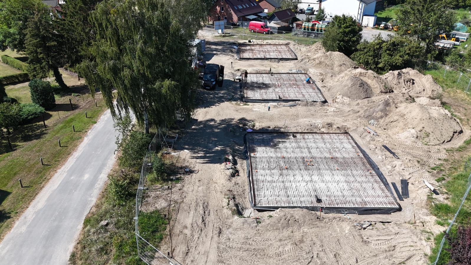 Zbrojenie fundamentów pod budowę w Szczecinie, widok z góry. Trzy kwadratowe obszary z siatką zbrojeniową, przygotowane do zalania betonem. Prace budowlane w toku.